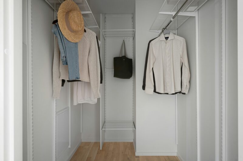 A white closet with a hat and coat rack